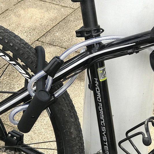 Heavy-duty U-lock with steel cable securing black mountain bike to metal pole, bike security