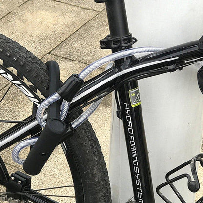 Heavy-duty U-lock with steel cable securing black mountain bike to metal pole, bike security